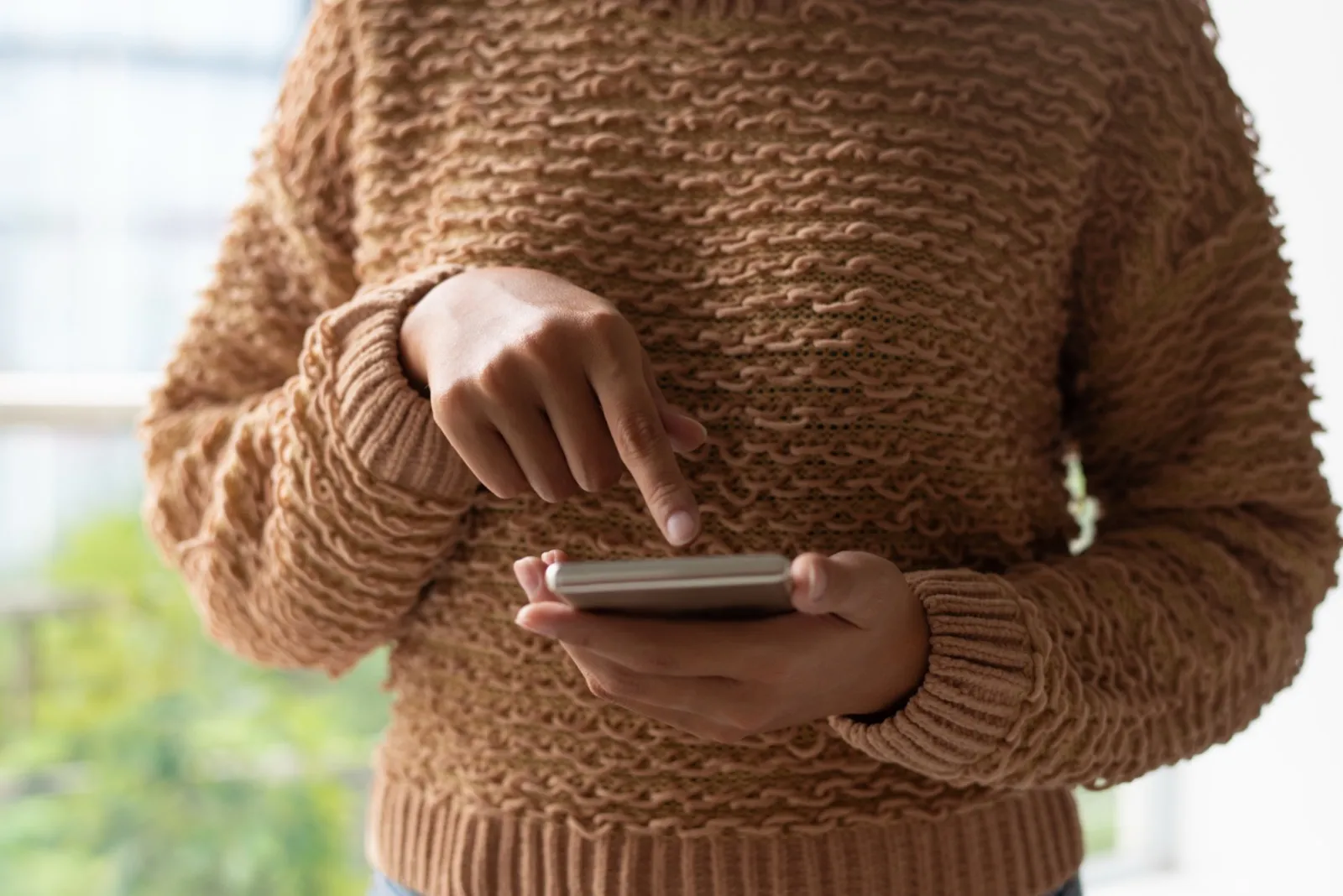 A hand scrolls a phone held close to the camera.