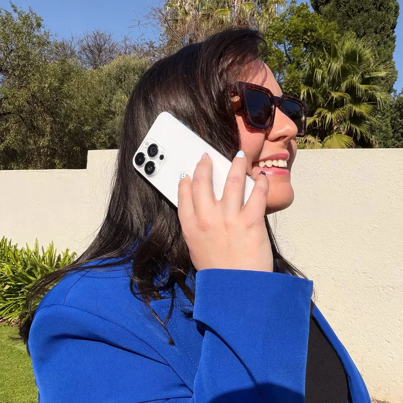 Georgia May outdoors in sunglasses, taking a call.